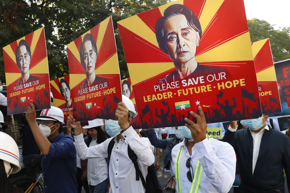 People at a protest hold signs with Aung San Suu Kyi's image and 'Please Save Our Leader - Future - Hope.'