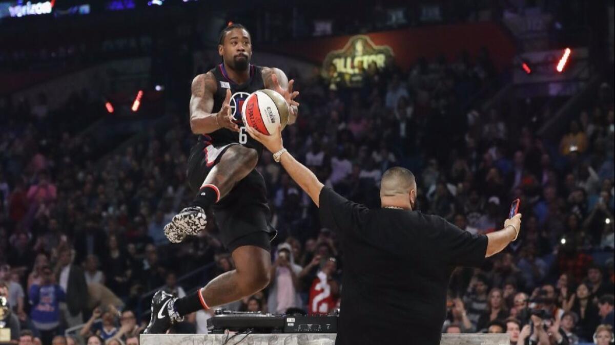 Clippers center DeAndre Jordan leaps over D.J. Khaled's turntables on Saturday during the slam-dunk contest in New Orleans.