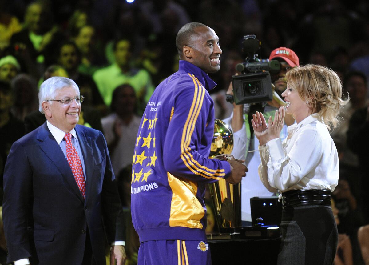 Kobe Bryant smiles after receiving his championship ring from NBA commisioner David Stern, left, and Jeanie Buss on Oct. 27, 2009, at Staples Center. 