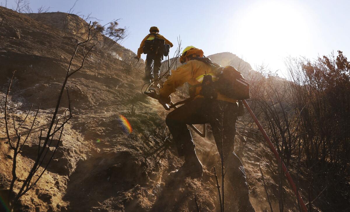 Firefighters John Kafoury, left, and Matt Petro with the Orange County Fire Authority assist Los Angeles County firefighters working to gain containment of a wildfire that is burning in the Placerita Canyon area of Santa Clarita.