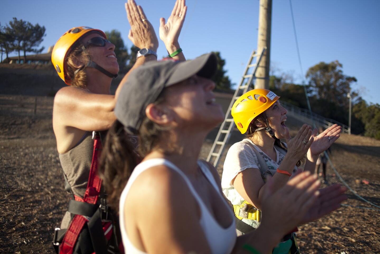 Angela Piatelli, left, an attendee (who wished to remain unnamed), center, and Jolie Schooler cheer on women participating in the ropes course at the Gindling Hilltop Camp during Campowerment.