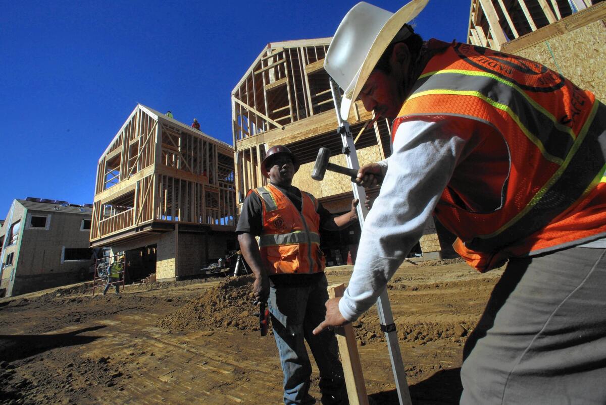 Francisco Valdea, left, and Efrain Trejo work on leveling ground for parking and driveways for homes being built in Echo Park.