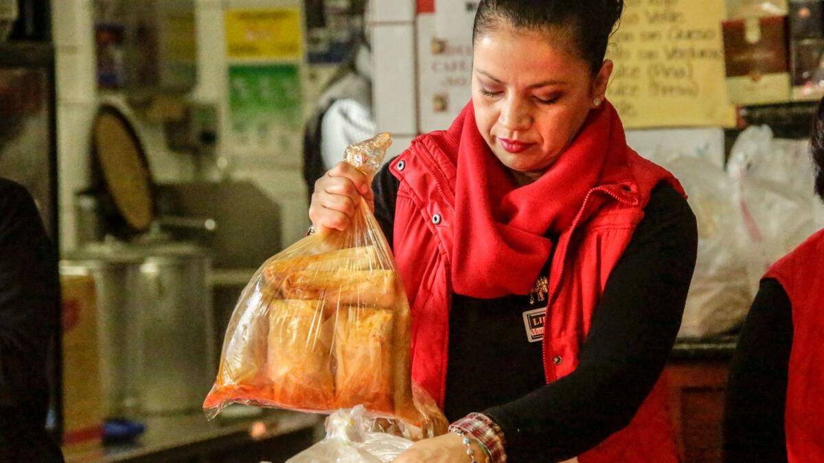 Monica Acosta packs some fresh tamales for the customers who line up early in the morning to purchase Christmas tamales at Tamales Liliana's Restaurant in Los Angeles.