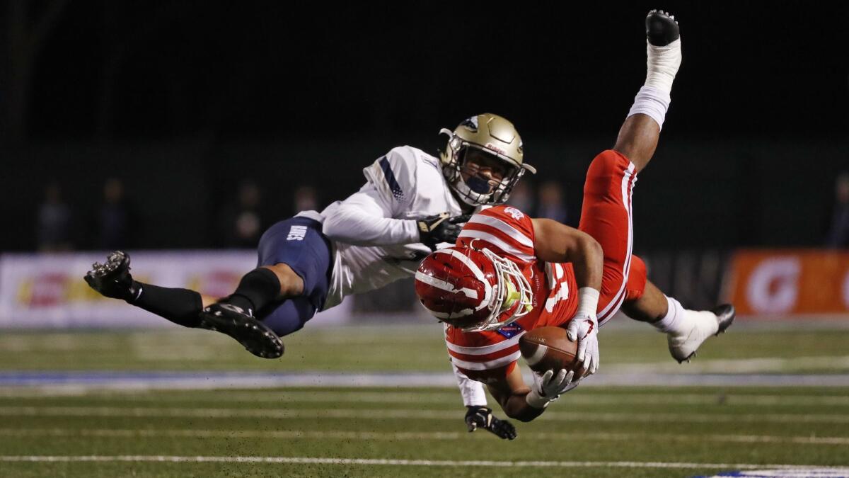 Mater Dei running back Glenn Harper (15) hangs onto the ball after being upended by St. John Bosco defensive back Chris Steele during last season's Trinity League game. The two players are back for the 2018 edition of the game.