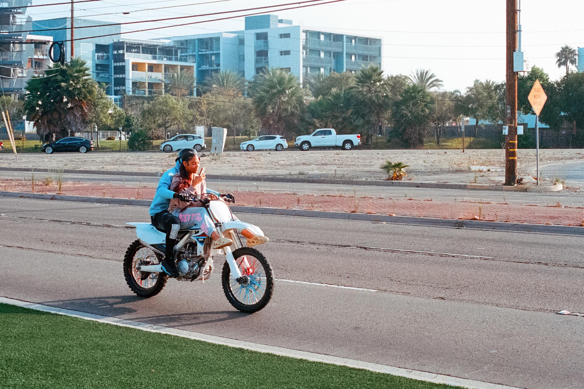 Two people zoom by on a bike.