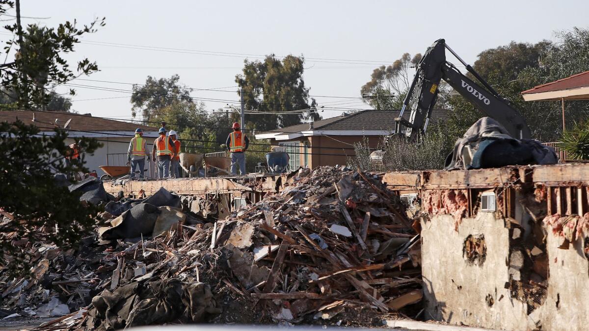 Workers demolish the rear portion of the former Costa Mesa Motor Inn on Tuesday. The site at 2277 Harbor Blvd. will be redeveloped into an apartment complex.