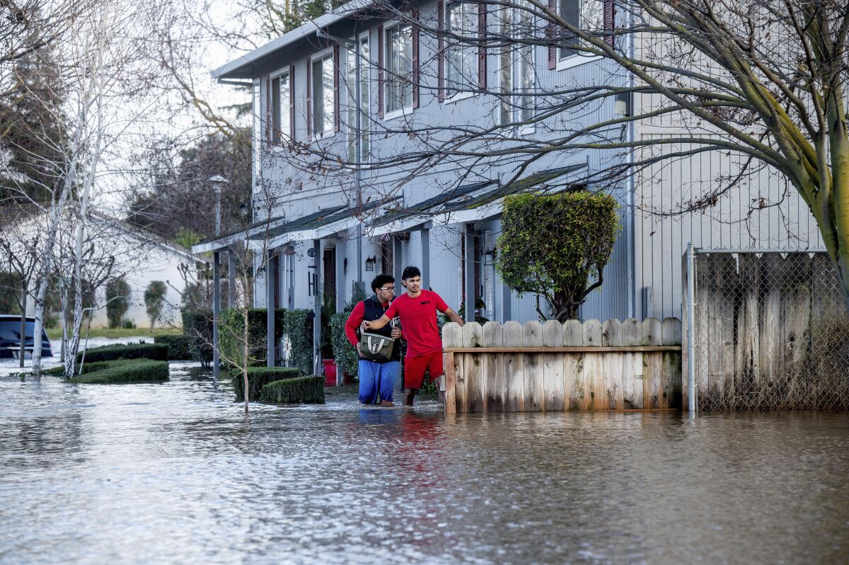 Two people wade through a flooded street 