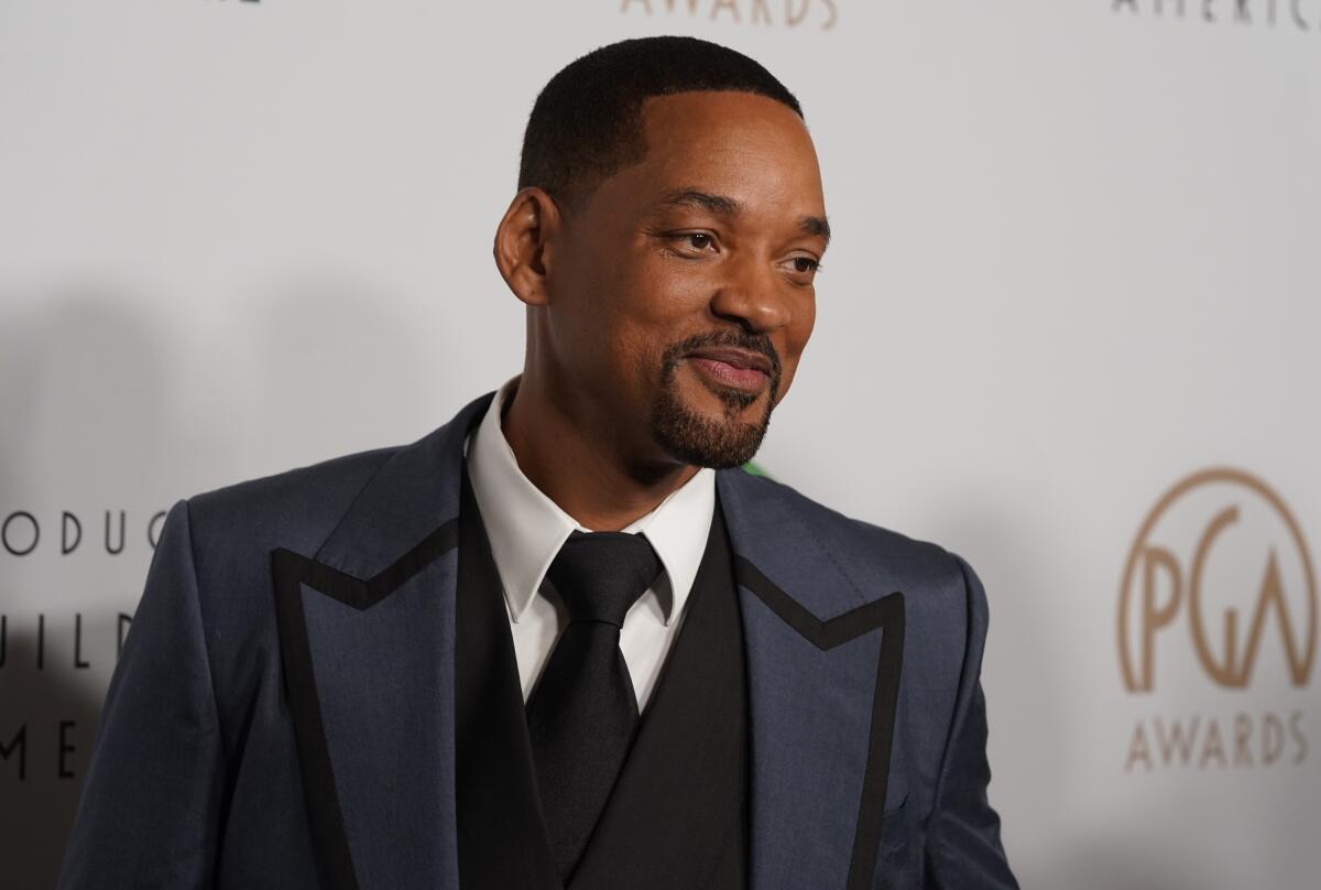Will Smith in a gray suit posing for pictures at a red carpet