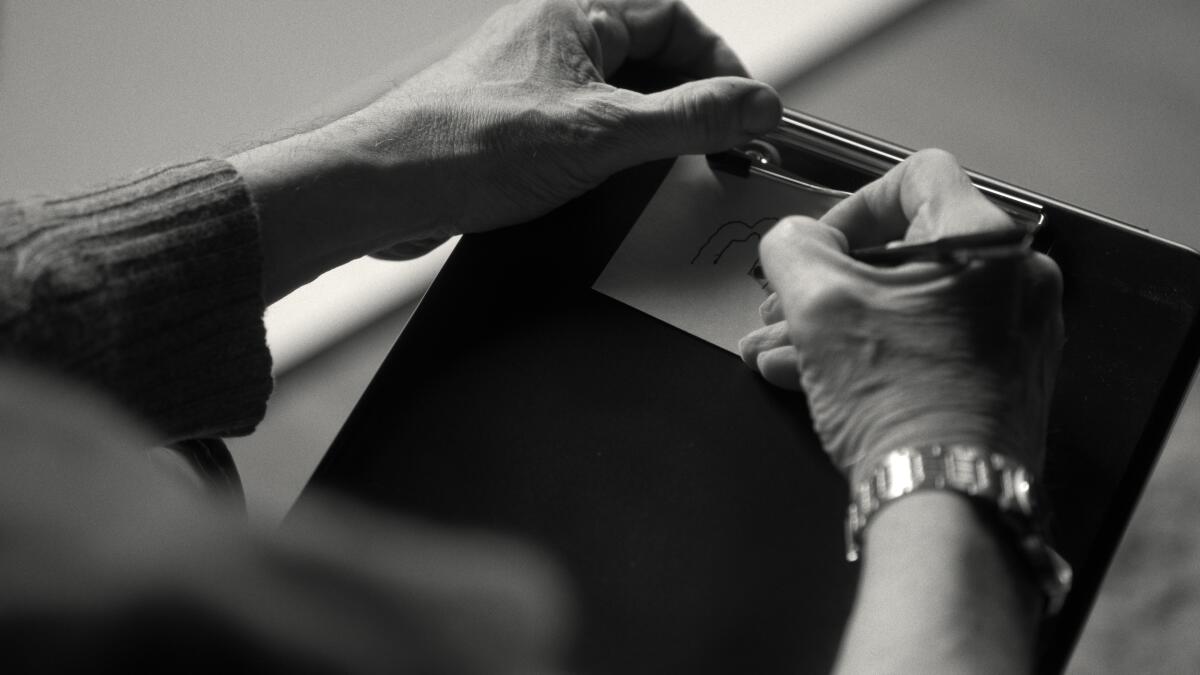 black and white photo of hands sketching on a clipboard