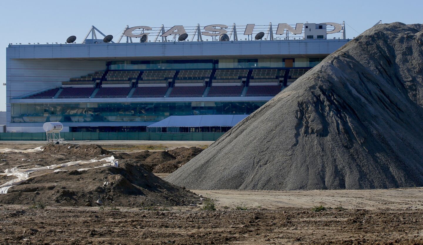 The grandstands and casino building at the former Hollywood Park in Inglewood are framed by a giant hill of crushed concrete where an NFL stadium will eventually be constructed.