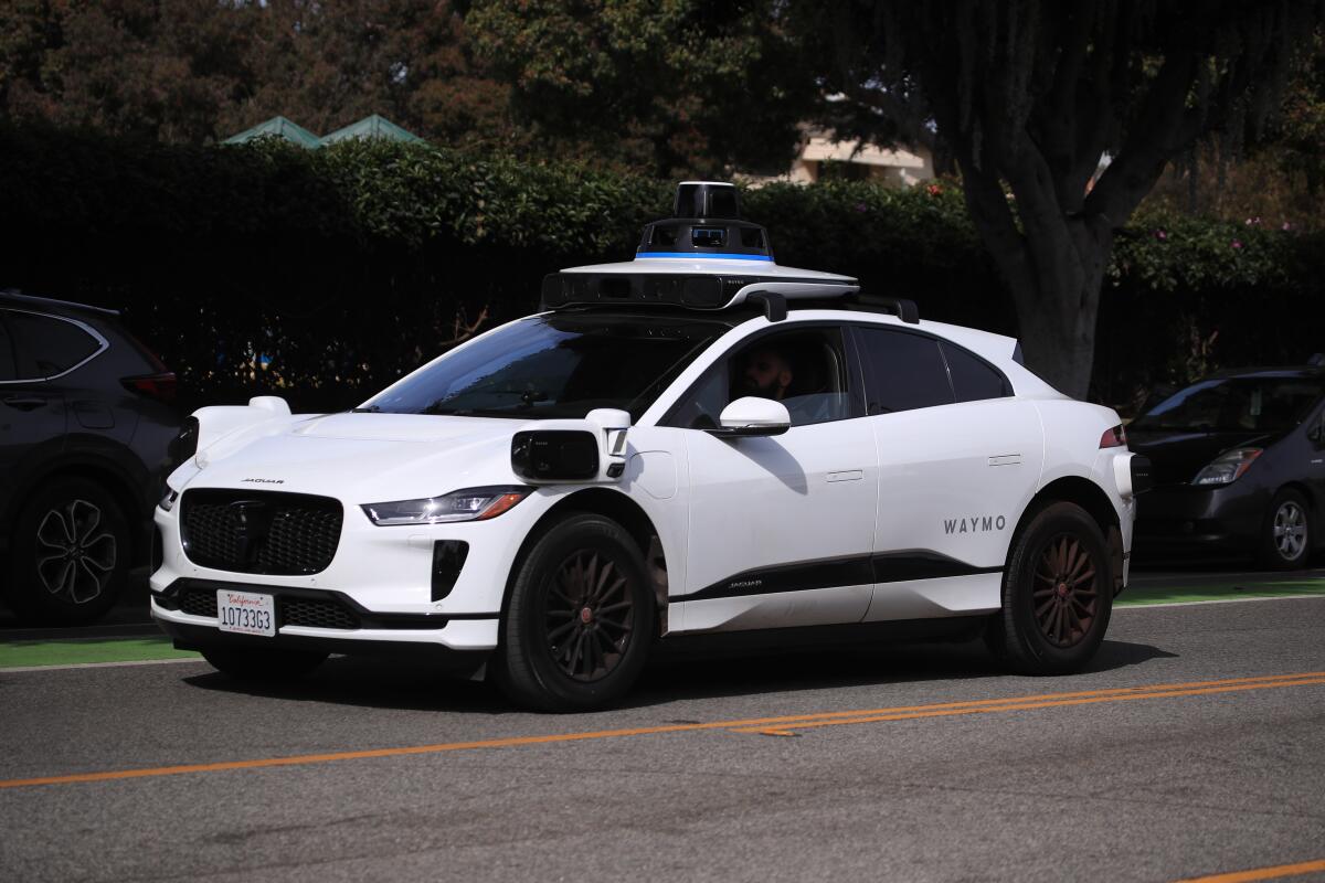 Passengers ride in an electric Jaguar I-Pace car outfitted with Waymo self-driving technology in Santa Monica.