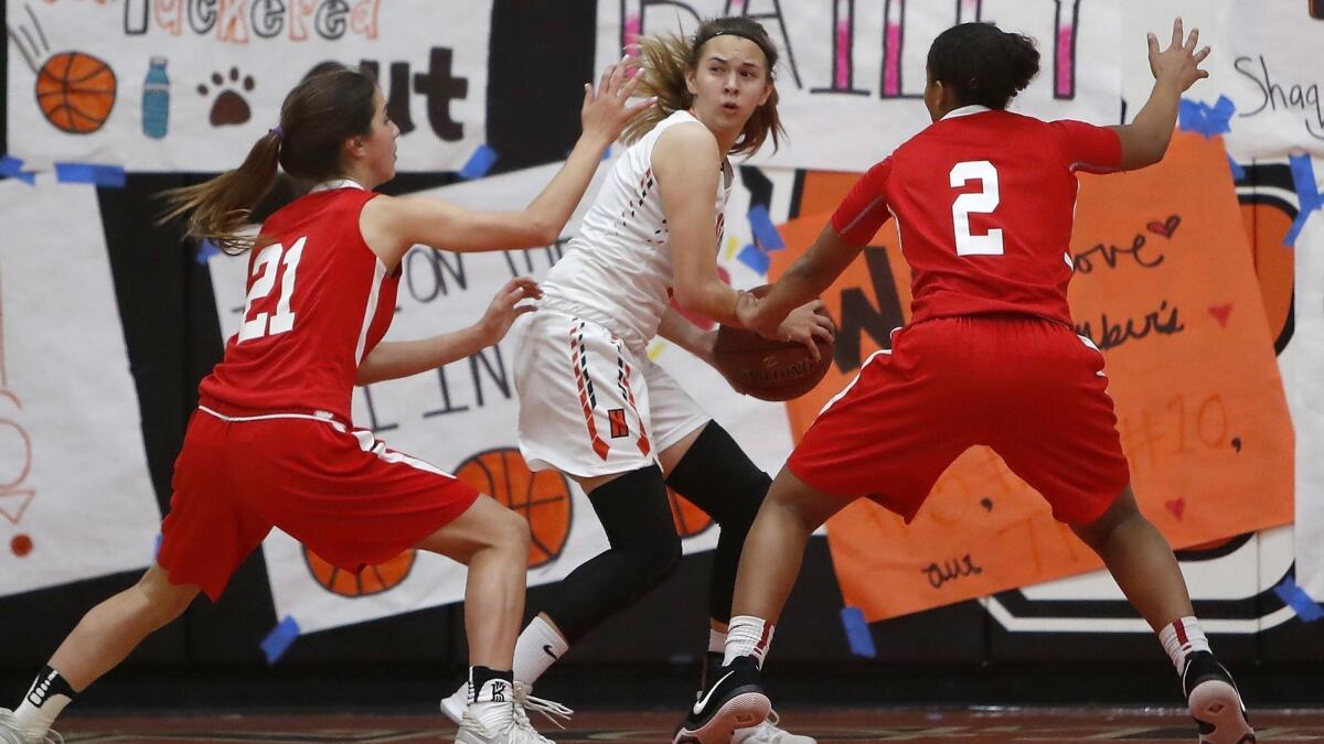 Huntington Beach High's Alyssa Real is trapped by two Los Alamitos defenders during the first half of a Sunset League game on Feb. 5, 2018.