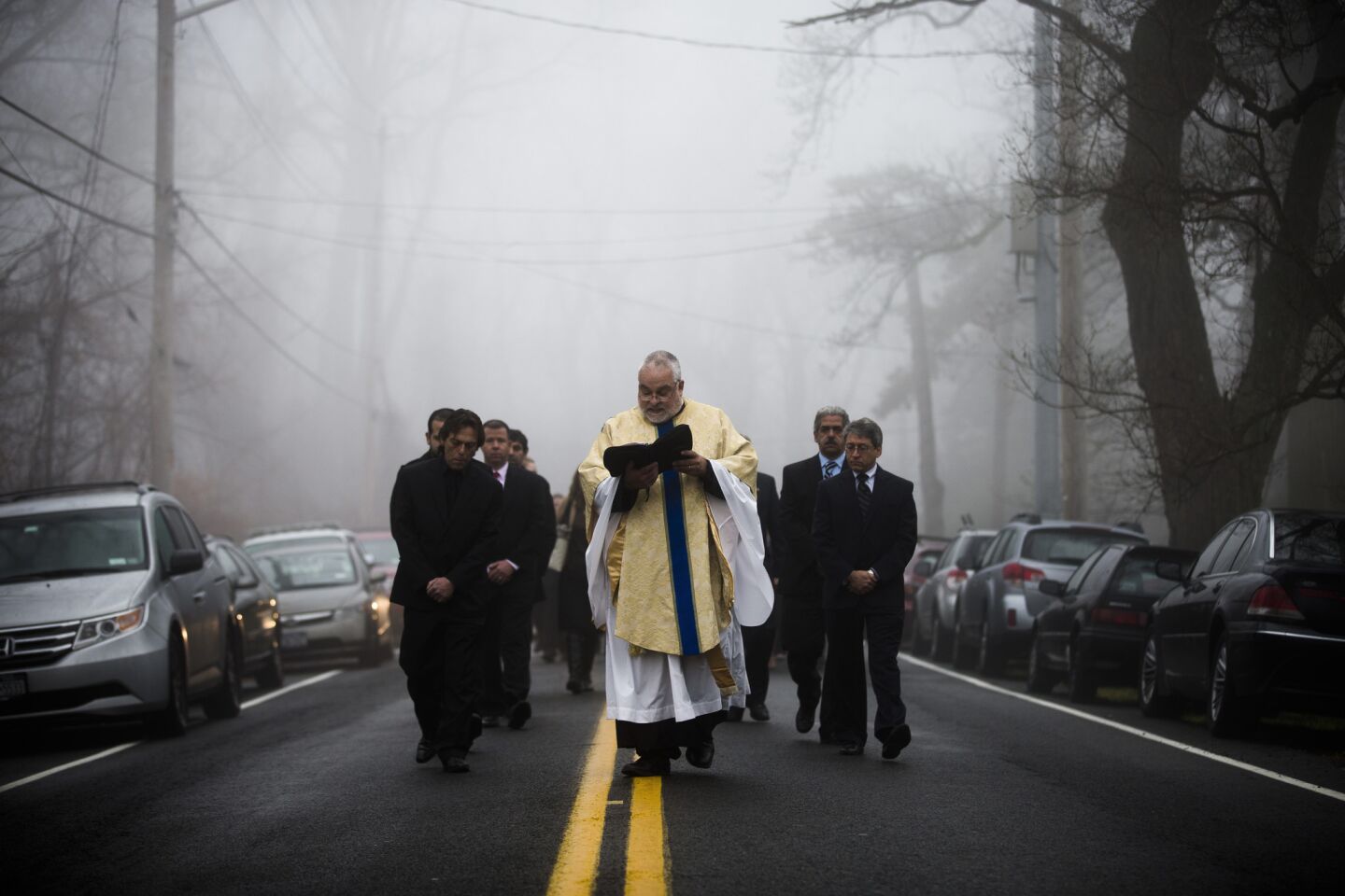 Father Eric Consentino and mourners follow a hearse carrying the casket of James Ferrari from the Church of the Divine Love toward his grave. Ferrari, 59, was killed along with three others when a speeding Metro-North Railroad train on the Hudson Line derailed in New York City.