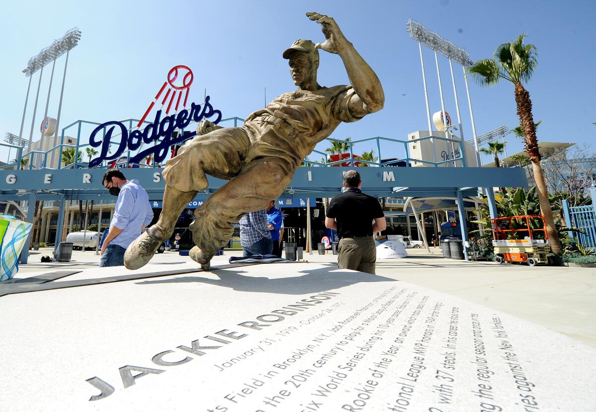 A statue, with the entrance to Dodger Stadium in the background, shows Jackie Robinson sliding. 