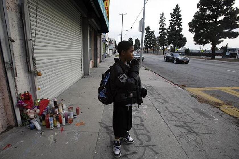 Keionta Hayes, 12, stands before a memorial of candles in the 10500 block of South Vermont Avenue, where his friend was shot earlier this month. The area is one of the deadliest in Los Angeles County.