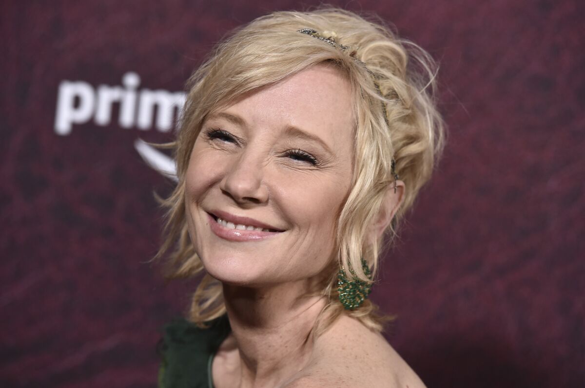 A woman with short blond hair and scrunched-up eyes flashes a big smile at an event