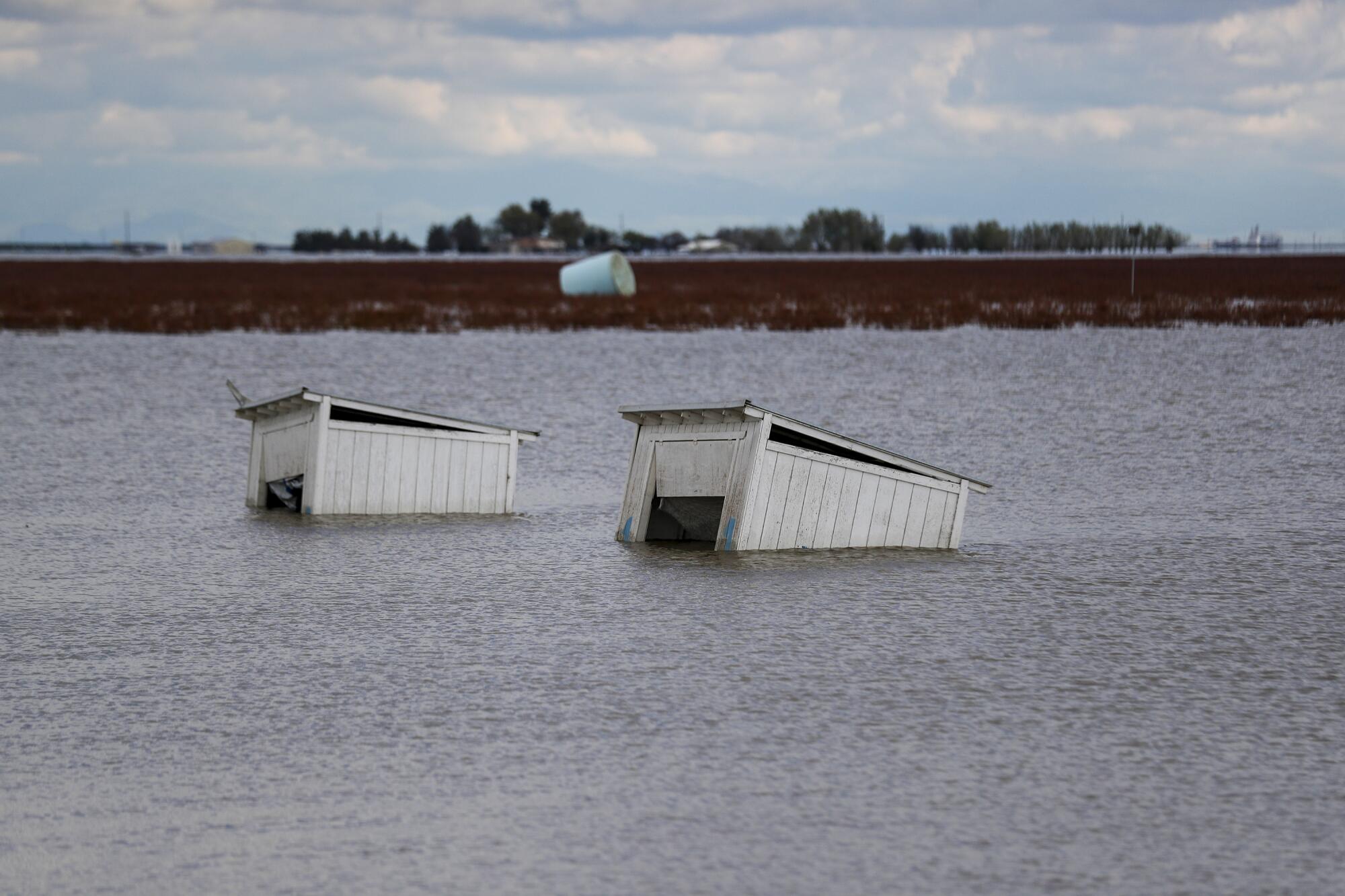 Two wooden structures are partly submerged in water.