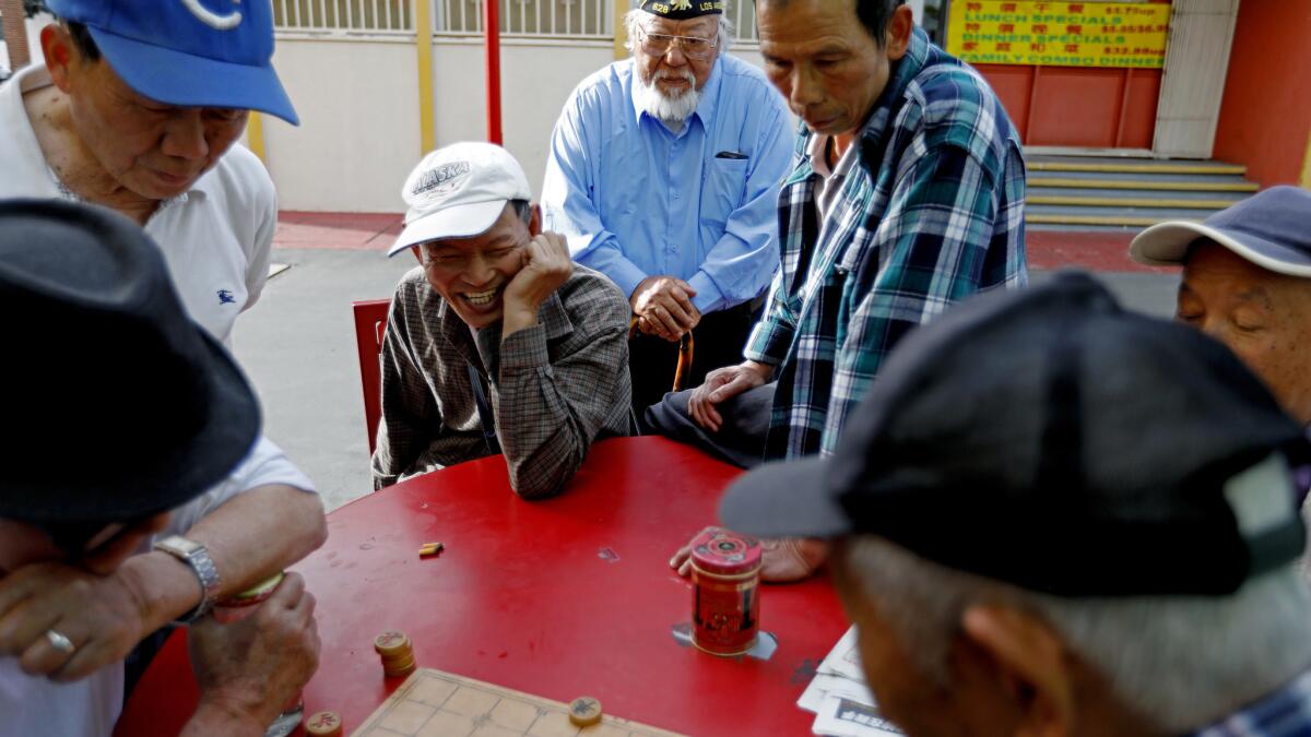 Jimmy Wong stops to watch a group of men play Chinese Chess while walking through Chinatown.