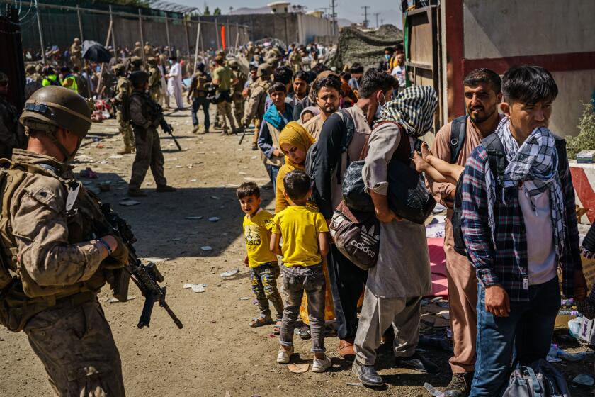 KABUL, AFGHANISTAN -- AUGUST 25, 2021: American soldiers watch over Afghan refugees waiting in line to be processed for an exit flight out of Kabul, Afghanistan, Wednesday, Aug. 25, 2021. (MARCUS YAM / LOS ANGELES TIMES)