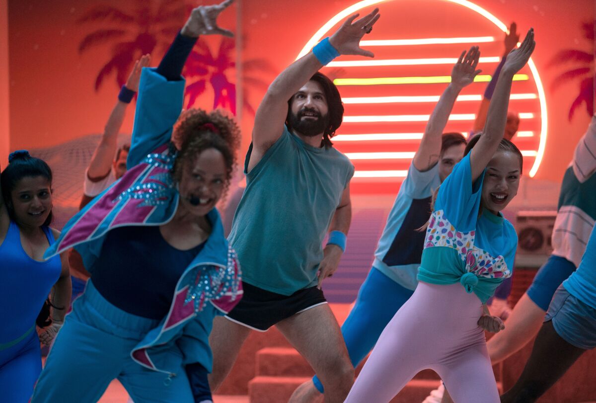 A man with a beard does aerobics with a group of women.
