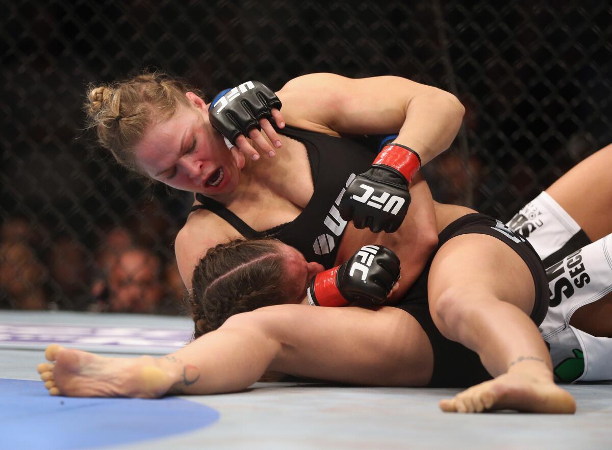 Ronda Rousey, about to submit Liz Carmouche, won her debut bout at Honda Center during UFC 157.