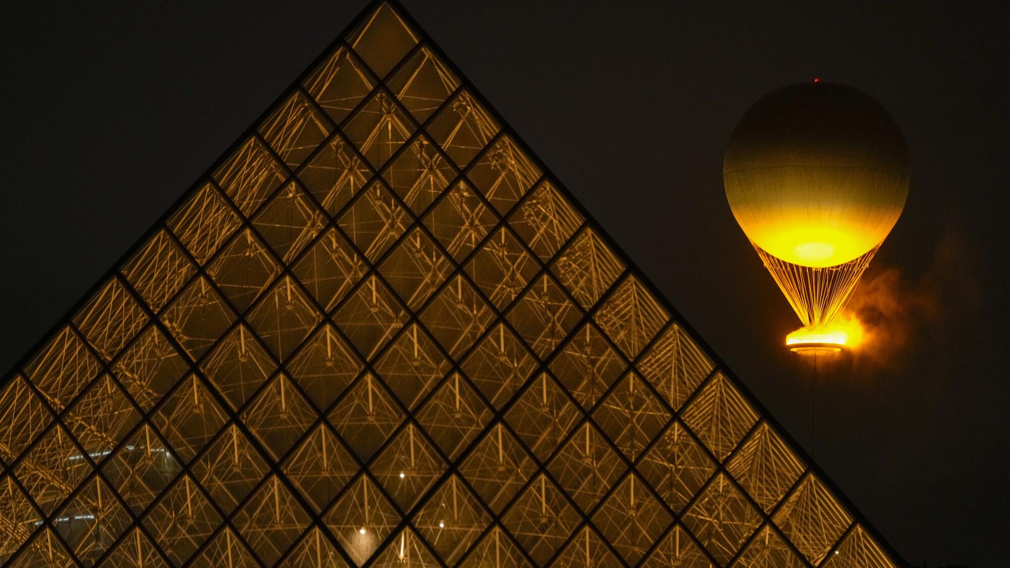 The Olympic flame rises on a balloon over the Louvre after being lit in Paris during the opening ceremony.