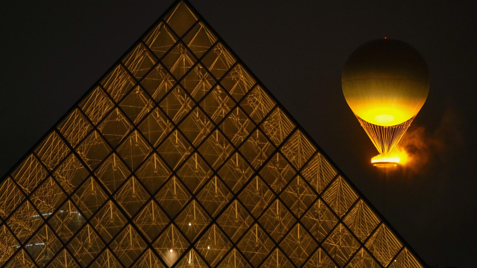 The Olympic flame rises in a balloon over the Louvre after being lit in Paris during the opening ceremony.