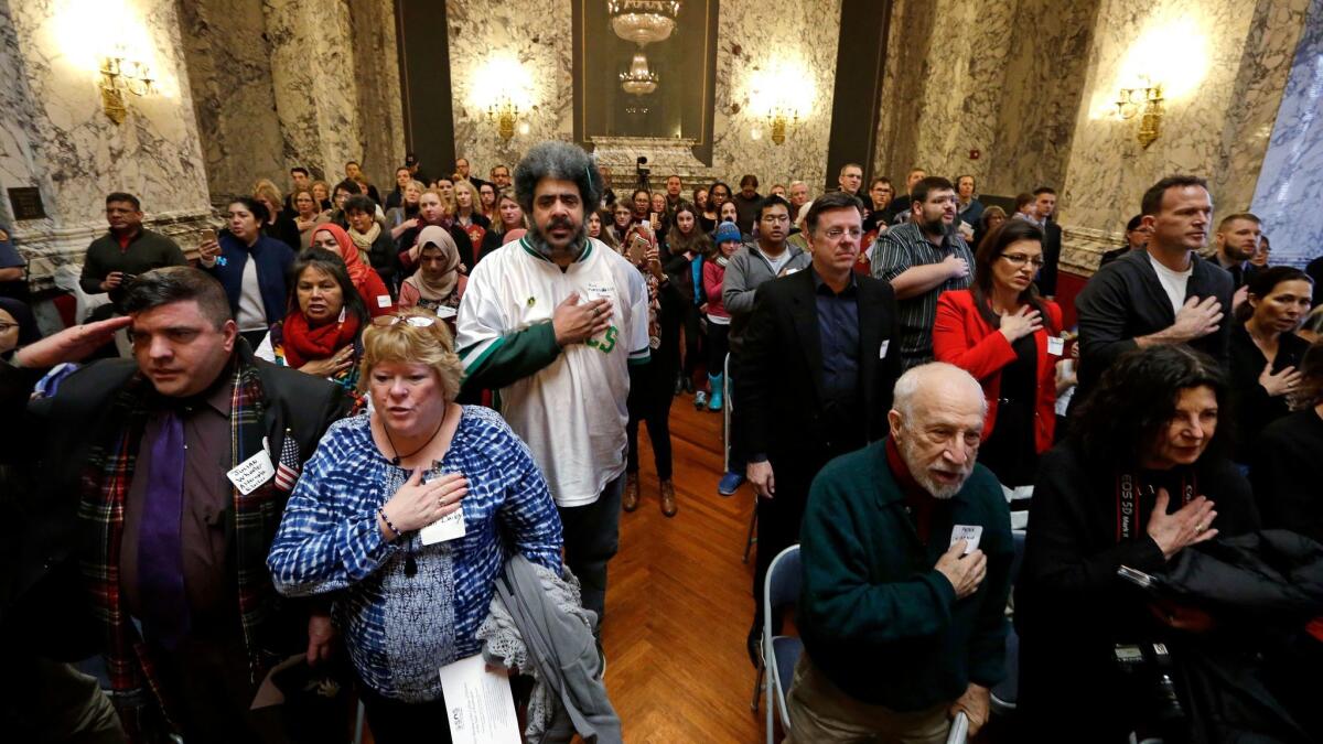 Spectators stand for the Pledge of Allegiance during a meeting of Washington state's electoral college in December.