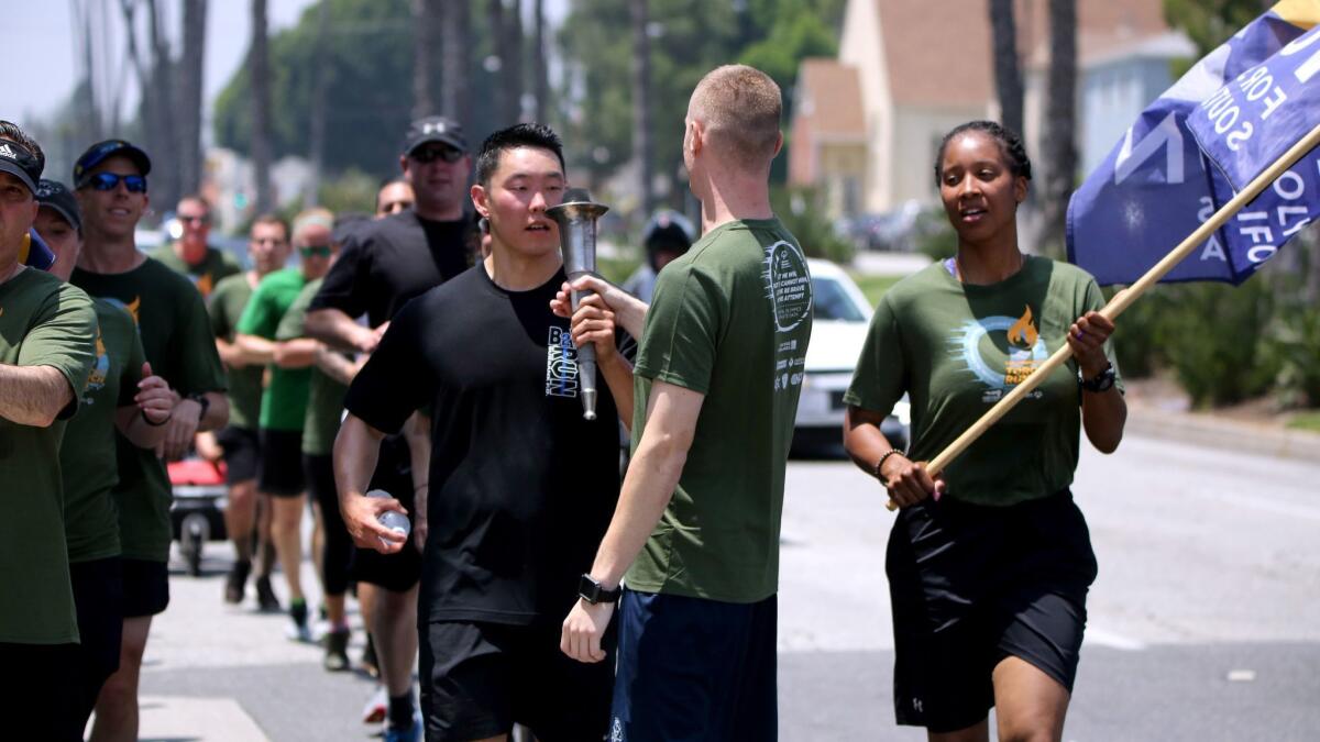 Burbank Police Officer Scott Choe, left, passes the torch to Glendale Police Officer Dacota Cummings during the Special Olympics torch run between the two cities on Wednesday.