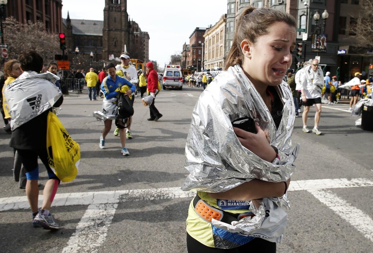 An unidentified Boston Marathon runner clutches a blanket around her shoulders as she walks near Copley Square after the bombing.