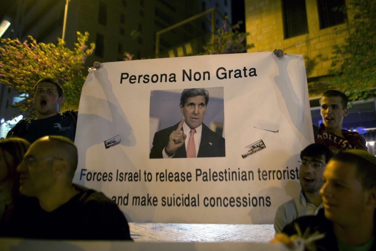 Demonstrators outside Secretary of State John F. Kerry's hotel in Jerusalem hold signs in protest of Israel releasing Palestinian prisoners.