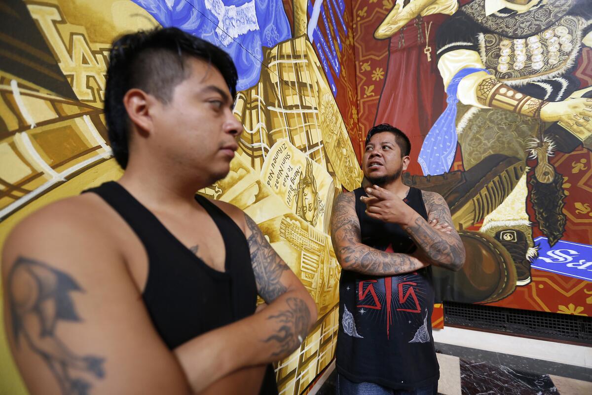 Artists Dario Canul, right, and Cosijoesa Cernas, from the Tlacolulokos artist collective in Oaxaca, Mexico, put finishing touches on their new murals in the Los Angeles Central Library's rotunda in September 2017.