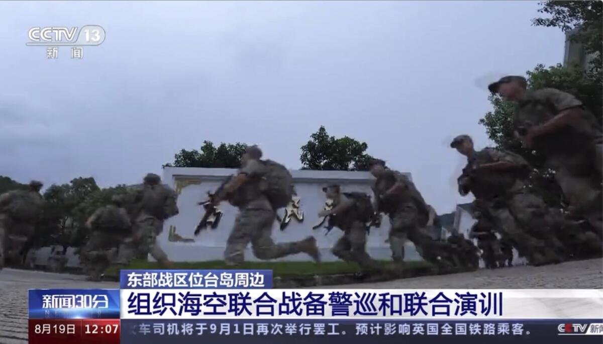 An image of video footage shows armed Chinese soldiers running on a field