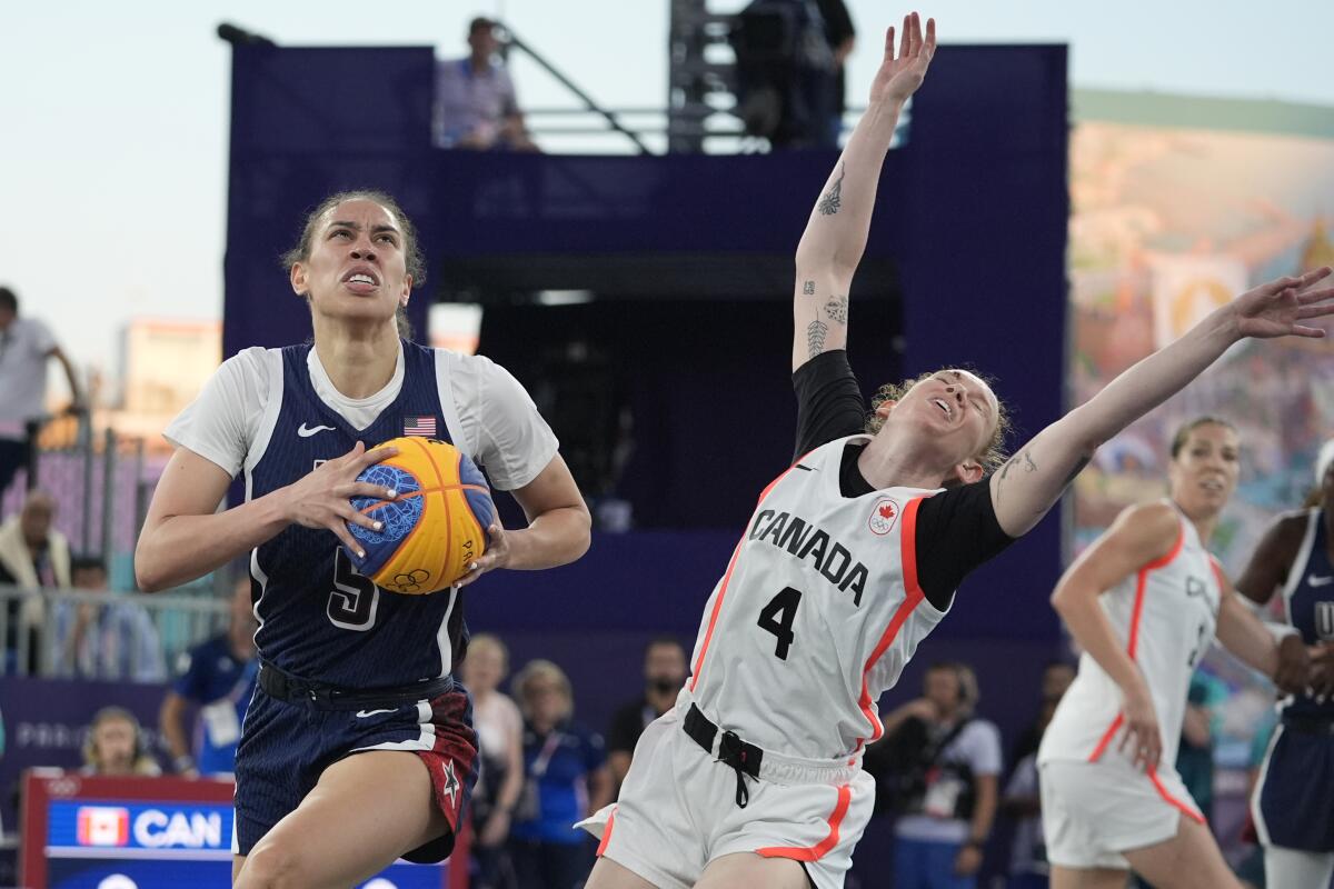 The United States' Dearica Hamby drives to the basket as Canada's Kacie Bosch guards her during women's 3x3 basketball 