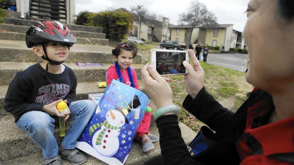 La voluntaria Jessica Yang toma una foto de los hermanos Majerid de 7 años, a la izq. y Jory de 4, refugiados sirios recién llegados afuera del nuevo apartamento de su familia en Dallas. Funcionarios de Texas han buscado una orden de la corte para bloquear que haya más reasentamiento sirio. / prensa asociada)
