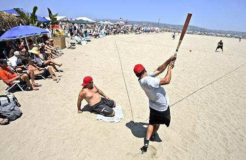 Jason Gracia of Corona hits the ball as team member Kevin Dolan, left, of Garden Grove, watches. Their team was competing in the 53rd annual Old Mission Beach Athletic Club Over-The-Line Tournament.