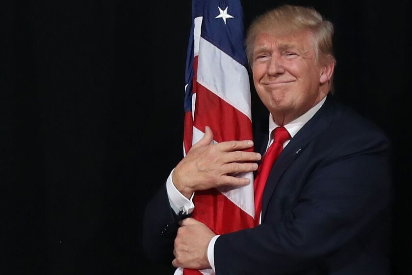 President-elect Donald Trump hugs the American flag at a campaign rally Oct. 24 in Tampa, Fla.