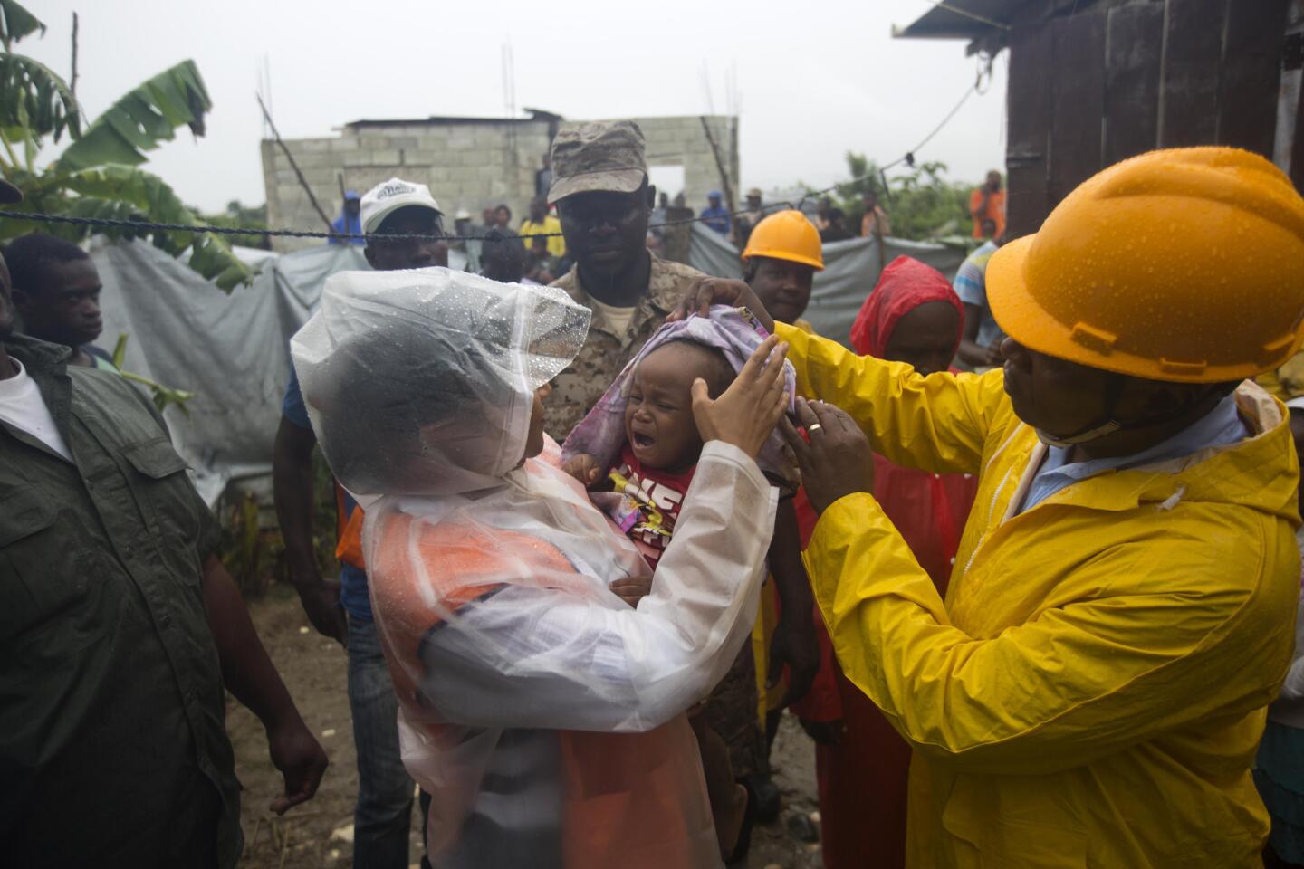 Nice Simon, the city mayor of Tabarre holds a baby as she helps people in the village to evacuate from the Tabarre river area in Haiti on Oct. 3, 2016.