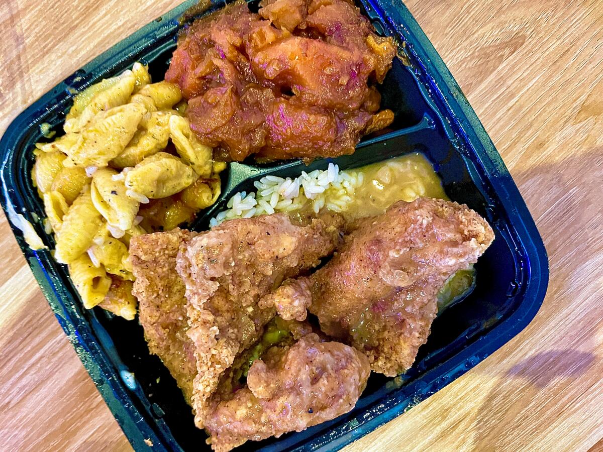 Turkey cutlets with rice and gravy, macaroni and cheese and candied yam in an open takeout container