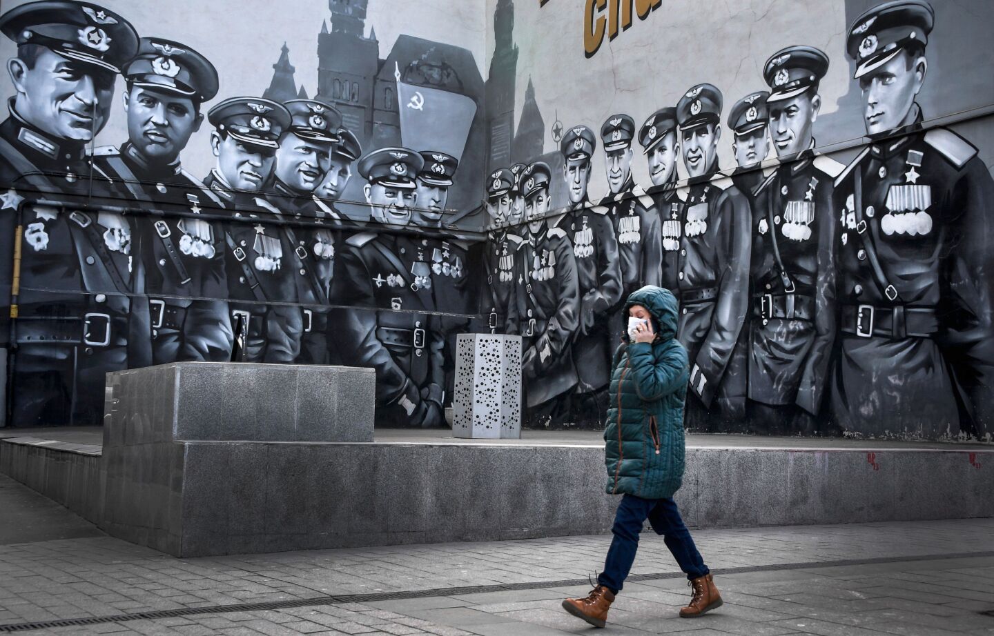 Russia: A woman wearing a face mask amid concerns about the coronavirus, walks past graffiti depicting Soviets in World War II.