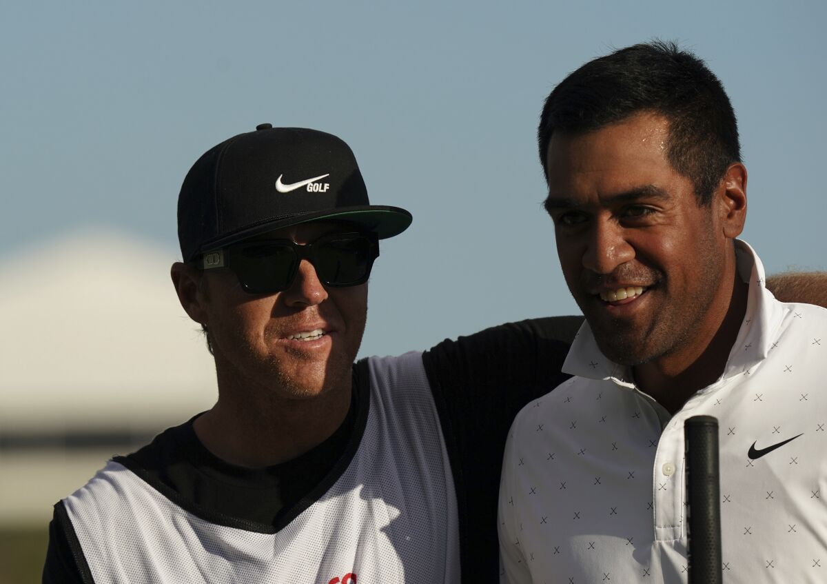 Tony Finau, of the United States, right, is congratulated by his caddie, Ryan Smith, owner of the Utah Jazz and co-founder the software firm Qualtrics, after sinking a birdie on the 18th hole during the second round of the Hero World Challenge PGA Tour at the Albany Golf Club, in New Providence, Bahamas, Friday, Dec. 3, 2021.(AP Photo/Fernando Llano)