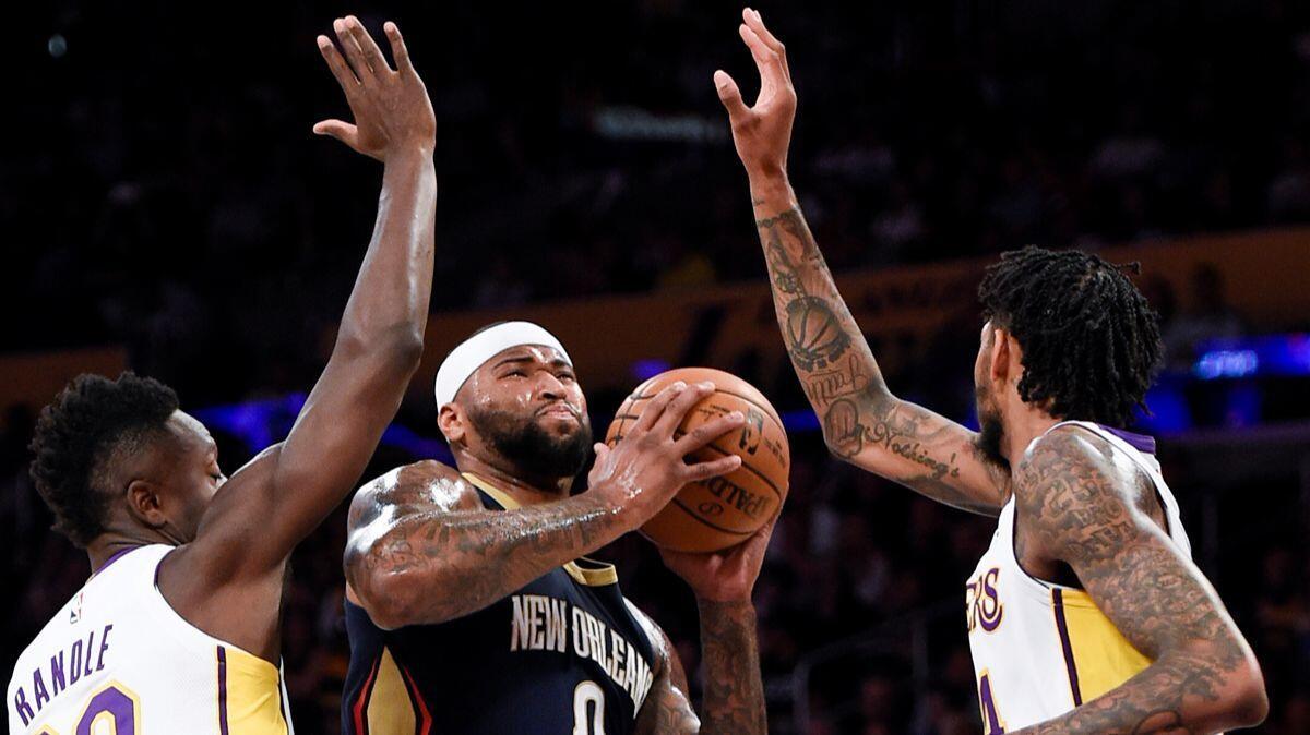 New Orleans Pelicans center DeMarcus Cousins, center, drives the ball between Lakers forward Julius Randle, left, and guard Brandon Ingram during the first half on Sunday.