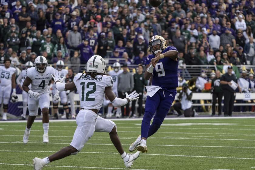 Washington quarterback Michael Penix Jr., right, throws a touchdown pass against Michigan State defensive back Chester Kimbrough during the first half of an NCAA college football game, Saturday, Sept. 17, 2022, in Seattle. (AP Photo/Stephen Brashear)