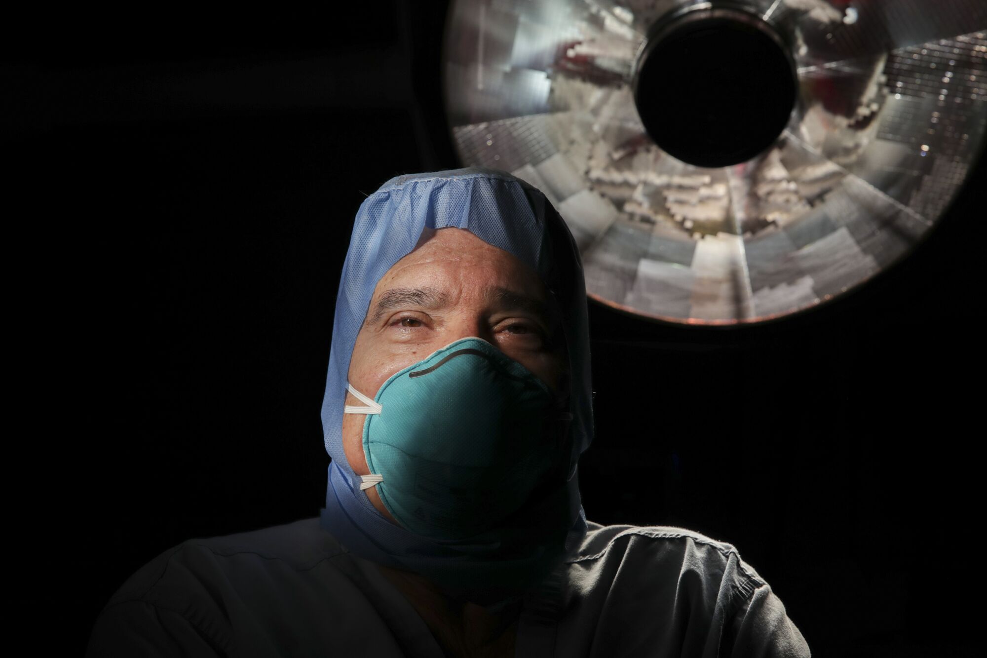 A surgeon wearing a face masks and scrubs, seen from below