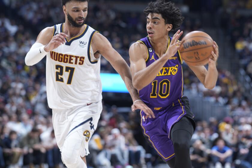 Los Angeles Lakers guard Max Christie, right, drives to the basket past Denver Nuggets guard Jamal Murray in the second half of an NBA basketball game Monday, Jan. 9, 2023, in Denver. (AP Photo/David Zalubowski)
