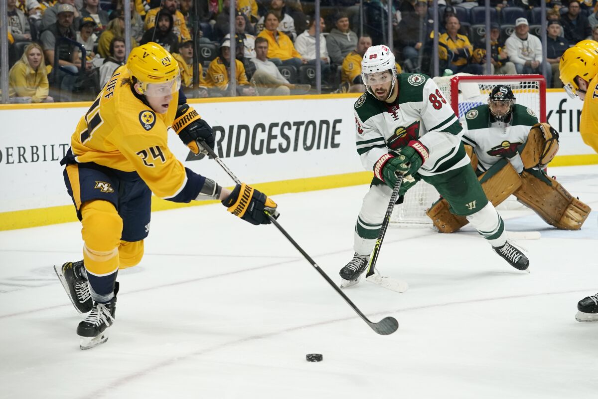 Nashville Predators' Matt Luff (24) is defended by Minnesota Wild's Frederick Gaudreau (89) in the second period of an NHL hockey game Tuesday, April 5, 2022, in Nashville, Tenn. (AP Photo/Mark Humphrey)