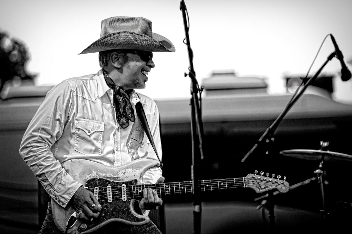Dave Alvin, in cowboy hat, plays his electric guitar