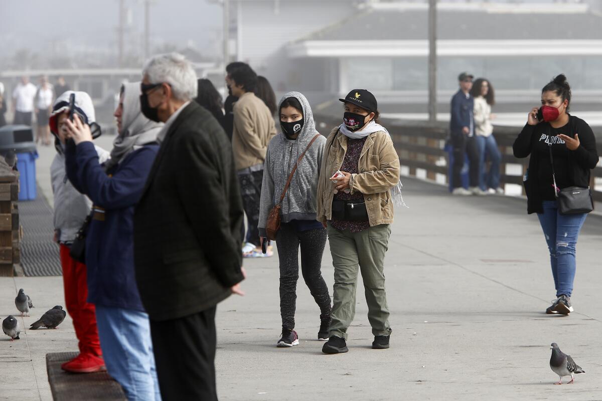 Visitors wearing masks at Newport Beach Pier on Thursday.