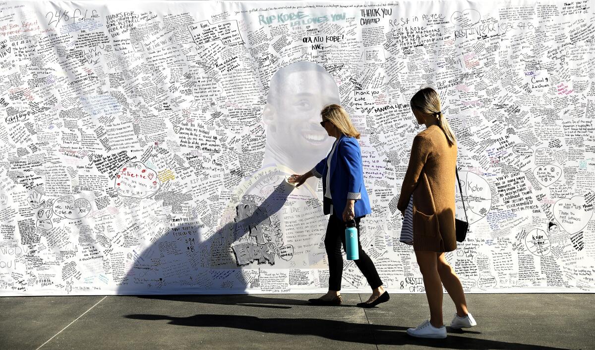 People leave messages for Kobe Bryant on a memorial at the Lakers' training facility in El Segundo.