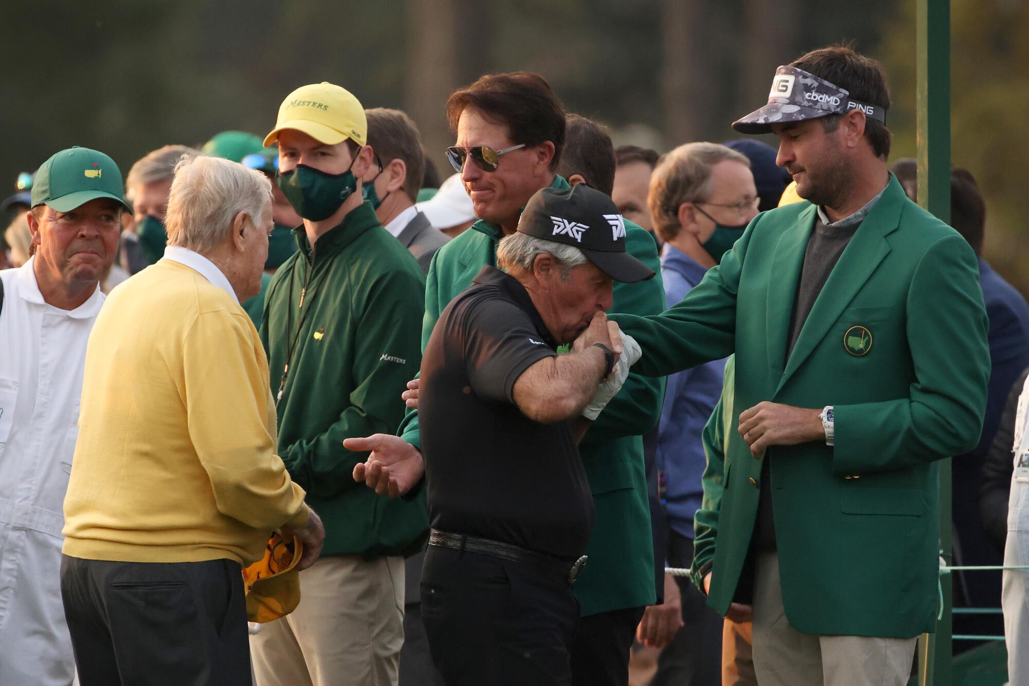 Gary Player playfully kisses the hand of Bubba Watson. At left, Jack Nicklaus greets Phil Mickelson. 